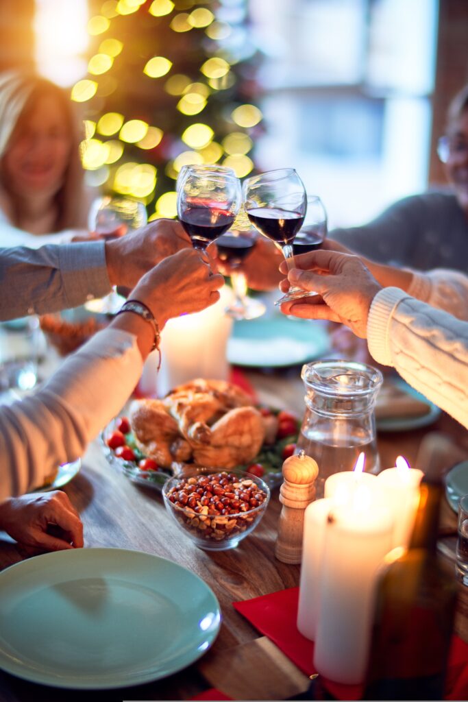 A small party toasting each other to red wine at a table full of food