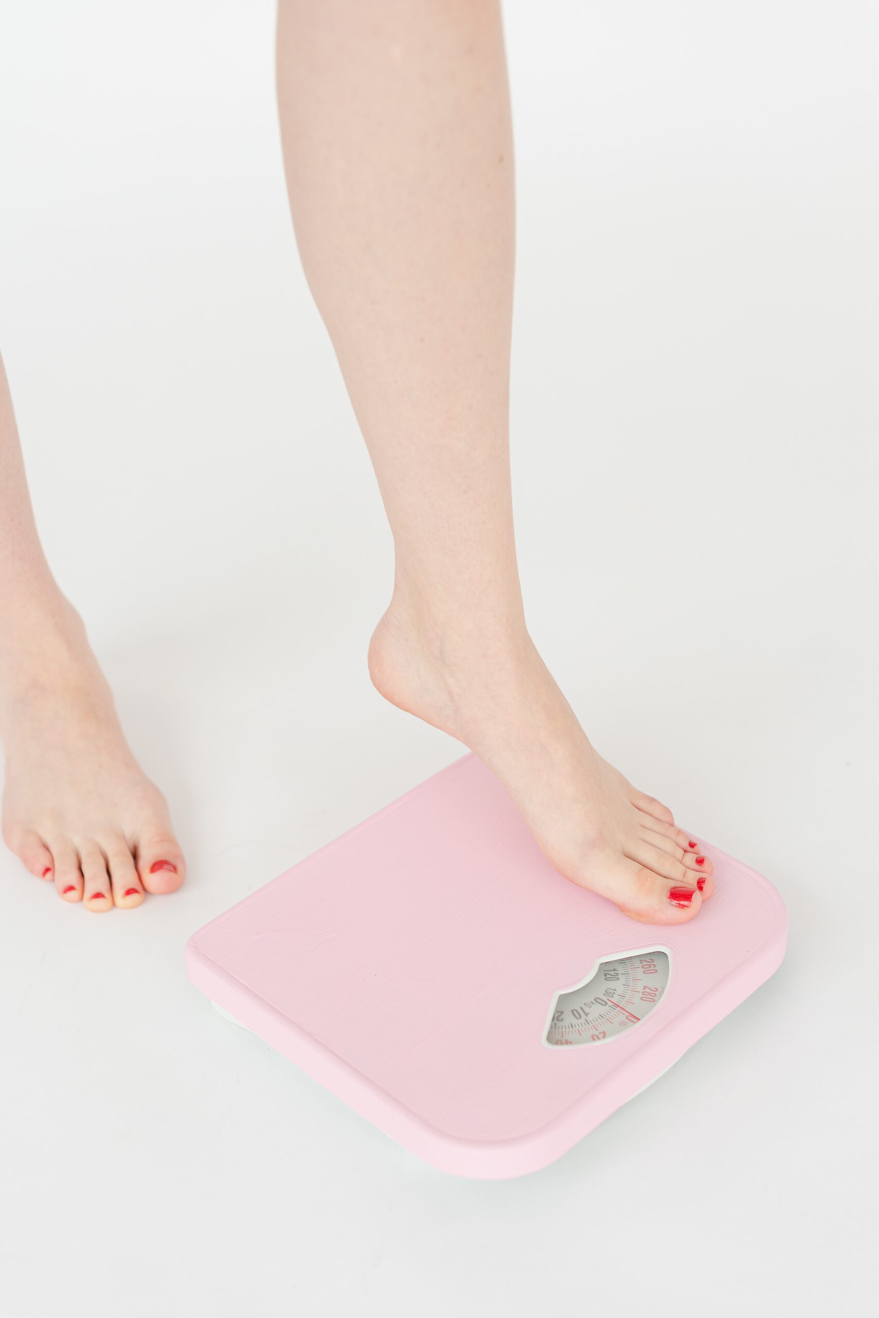 Leg of a lady on a pink weighing scale