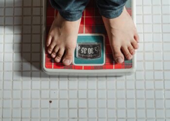 A person weighing themselves on a red and green retro looking weighing scale