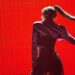 lisa manoban dressed in performance outfit posing and standing against a red background