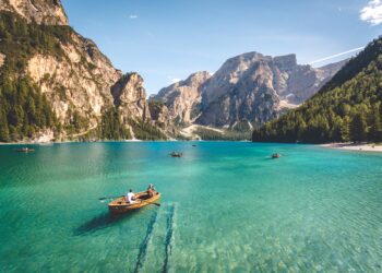 five brown wooden boat on blue lake water taken at daytime with mountains in the background