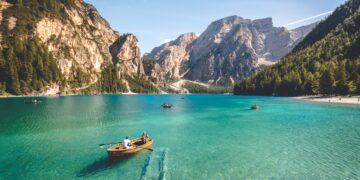 five brown wooden boat on blue lake water taken at daytime with mountains in the background