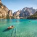 five brown wooden boat on blue lake water taken at daytime with mountains in the background