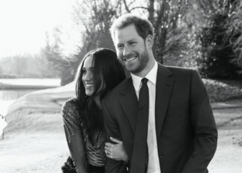 Monochrome photo of the Duke and Duchess of Sussex holding hands.