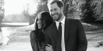 Monochrome photo of the Duke and Duchess of Sussex holding hands.