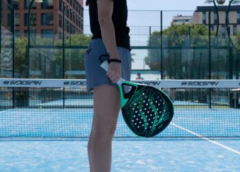 A woman holding a Padel tennis racquet on a tennis court