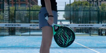 A woman holding a Padel tennis racquet on a tennis court